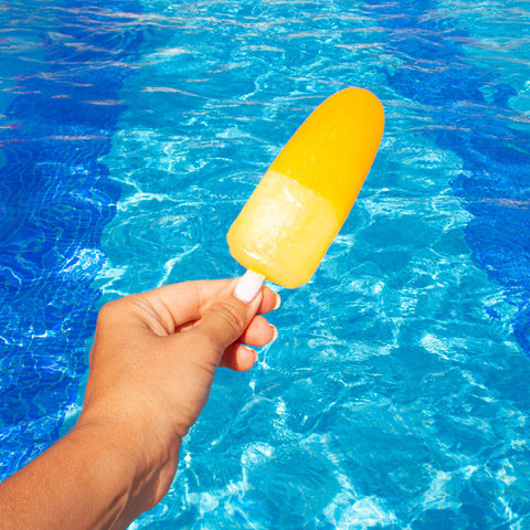 Yellow popsicle held out in front of pool