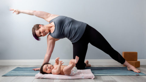 Woman doing yoga pose over her baby smiling down at him