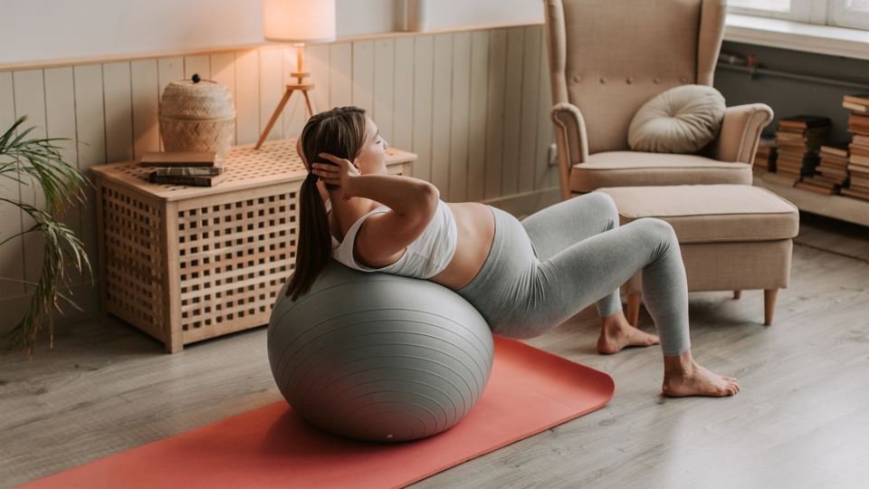 pregnant women performing ab exercises in living room