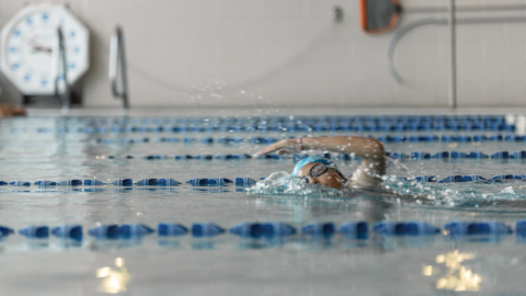 swim student performing side glide in an indoor pool