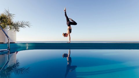 woman doing a handstand next to a pool