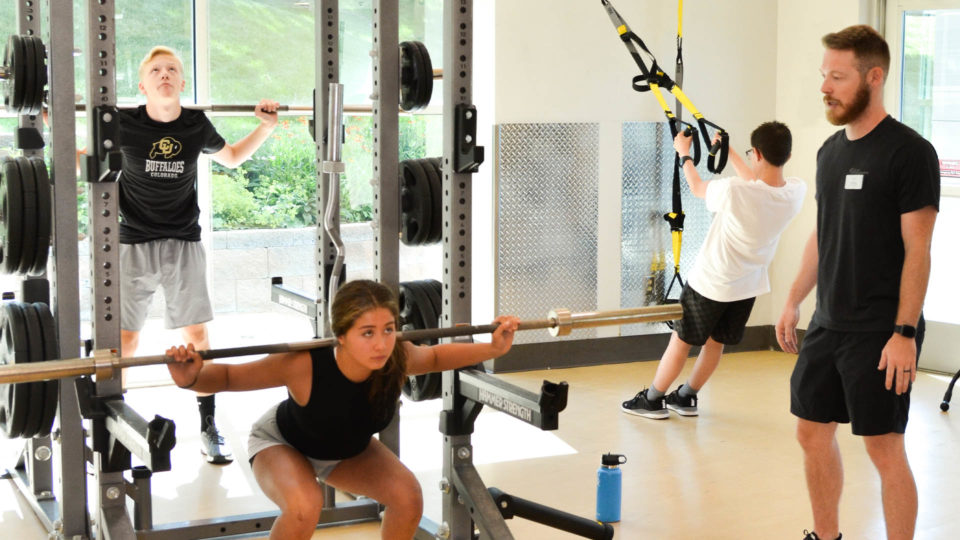 Teens Lifting Weights with Personal Trainer
