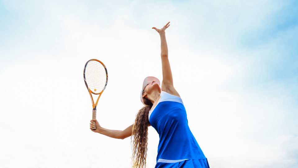 female tennis player in blue serving outside
