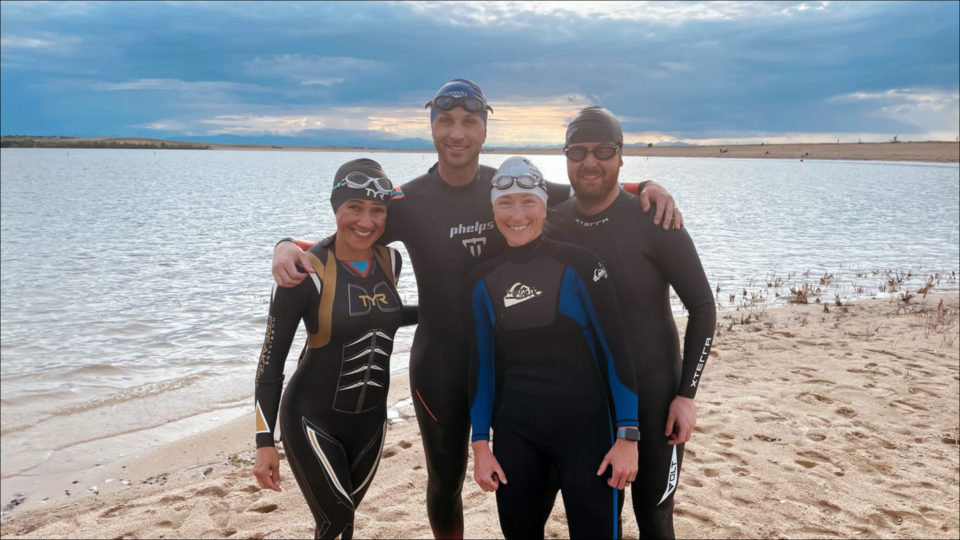 Group of 4 people in wetsuits participating in a triathlon