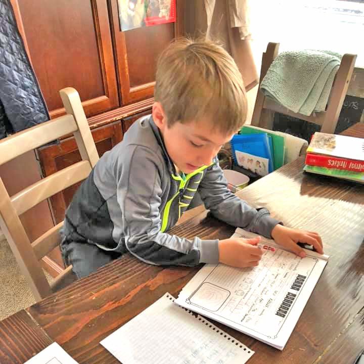 boy working on homework on a wooden table during the day
