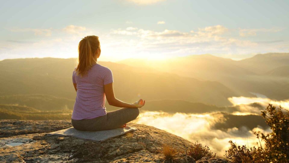 Lady meditating over a mountain