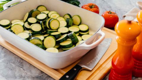 zucchini in a pan on a cutting board with tomatoes
