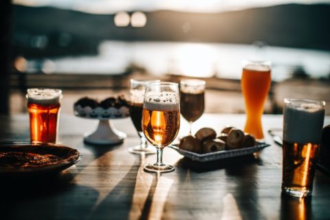 beer sitting on a table in the sunset by water