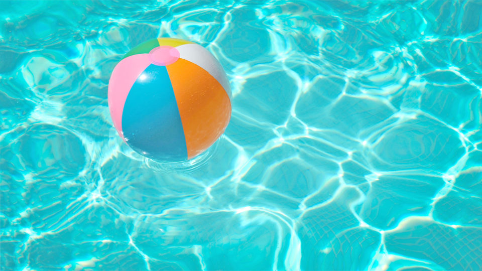 beach ball floating in pool water outside in the sun