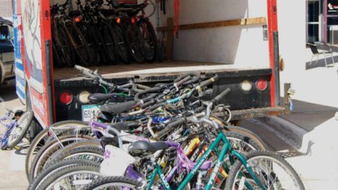 dozens of bikes sitting outside of a box truck to be shipped