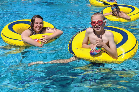 kids with thumbs up having fun in a swimming pool