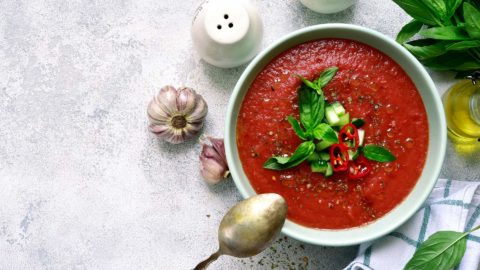 gaspacho soup with a spoon and veggies on a white table