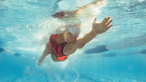 woman in an orange swim suit swimming laps in a pool
