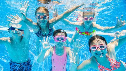 kids smiling underwater and wearing goggles