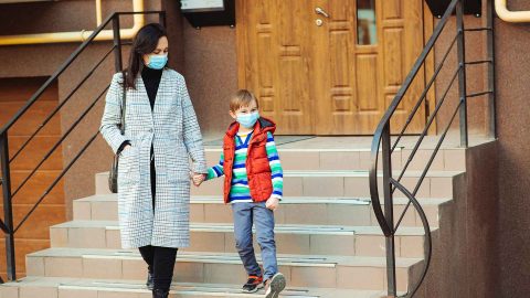 woman and son leaving their house wearing protective face masks