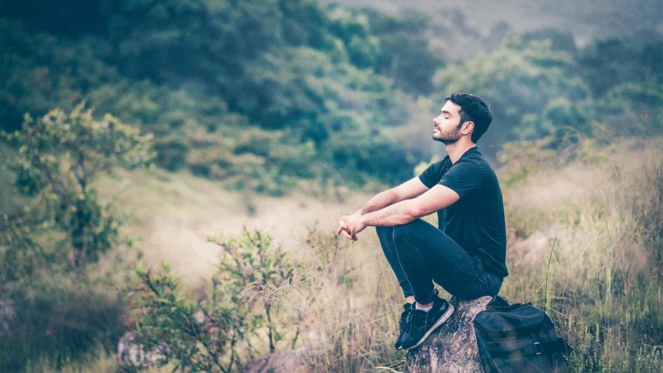 man sitting on rock in nature and breathing in