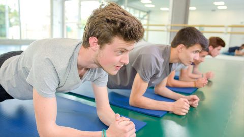 teen boys working out doing forearm planks on mats