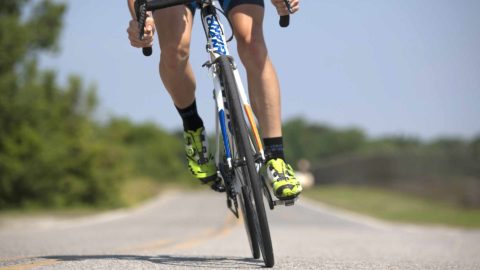 man cycling on a road bike outside during daytime in bright green shoes