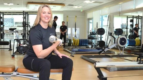 club greenwood personal trainer Jenny Stevens lifting a dumb bell and sitting