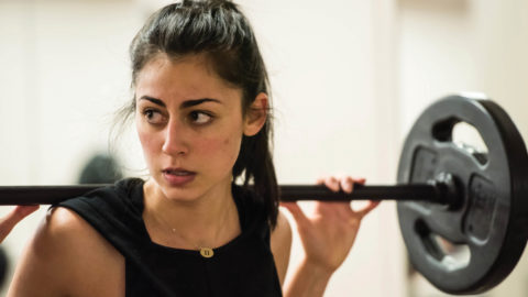 woman working out with weight on her shoulder